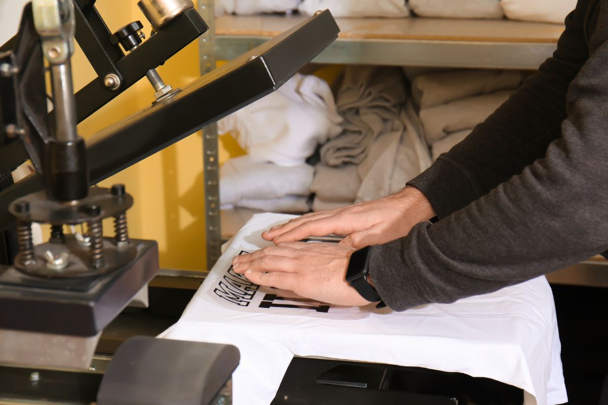 Homme utilisant une machine pour imprimer un t-shirt