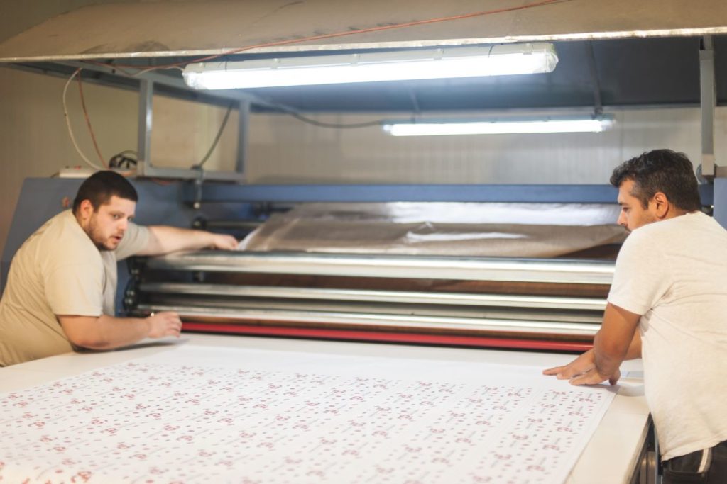 Deux hommes travaillant sur une machine de sublimation textile.